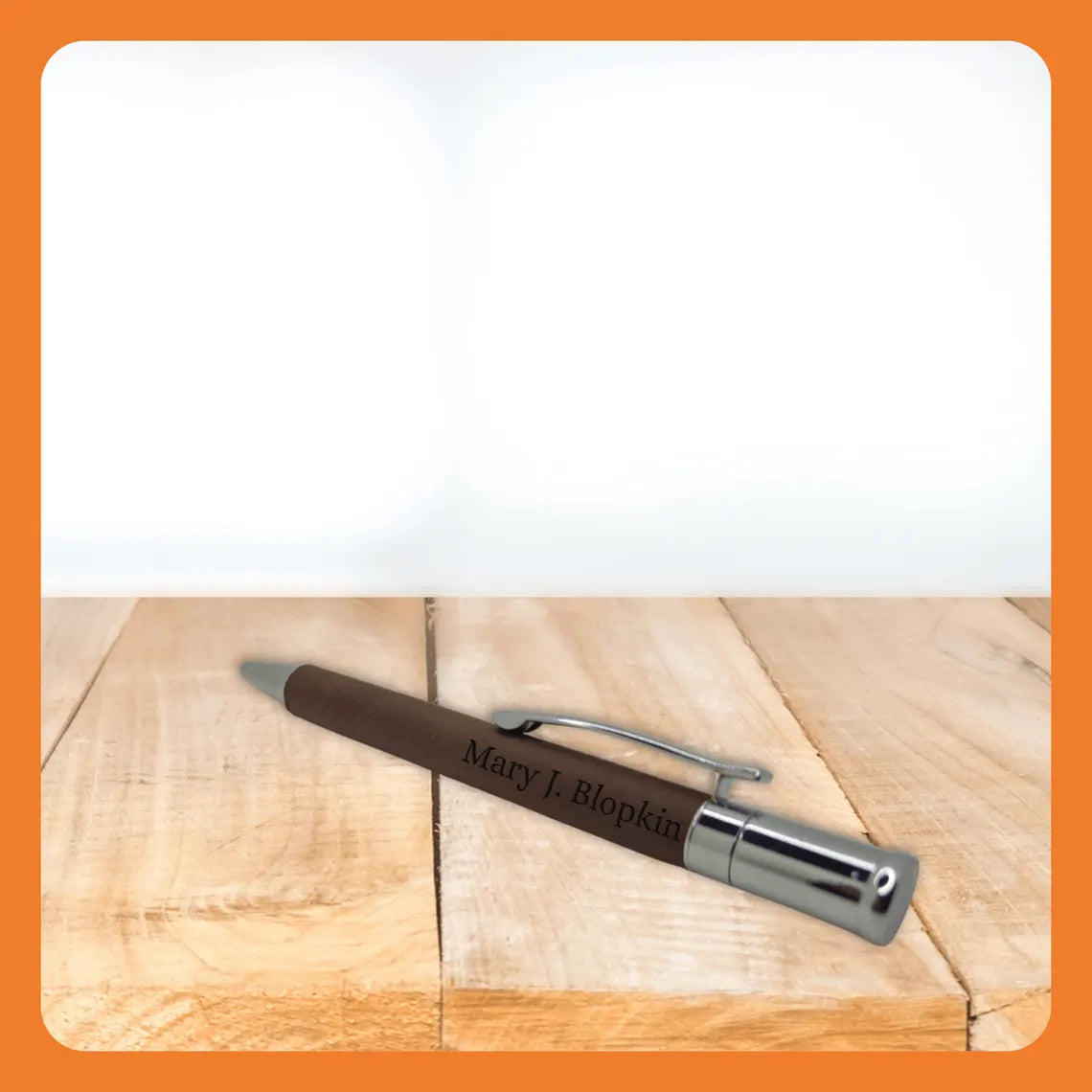 A personalized brown pen with a silver clip resting on a wooden surface.