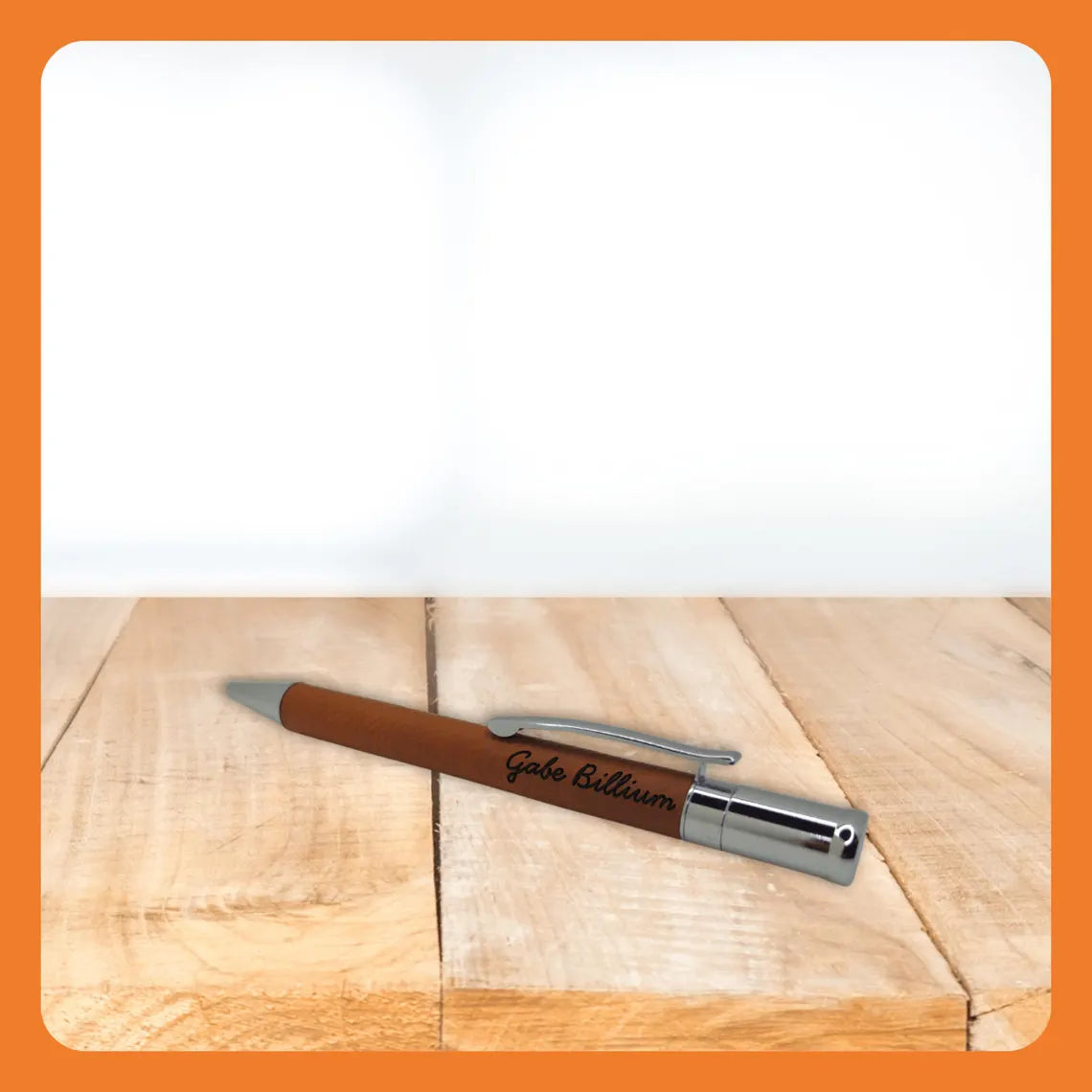 A brown pen with a silver clip resting on a wooden surface.