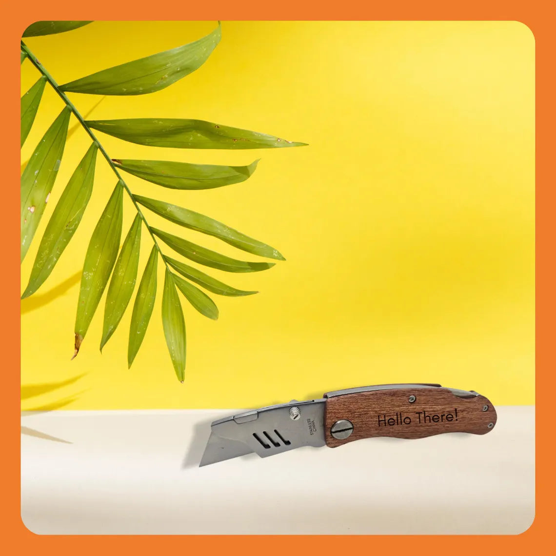 A pocket knife with a wooden handle and the words 'Hello There!' next to a green leaf against a bright yellow background.