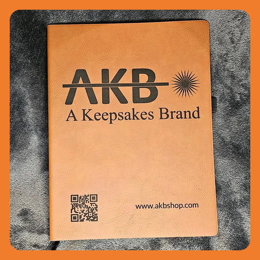 Brown leather notebook with the text 'AKB A Keepsakes Brand' and a QR code.