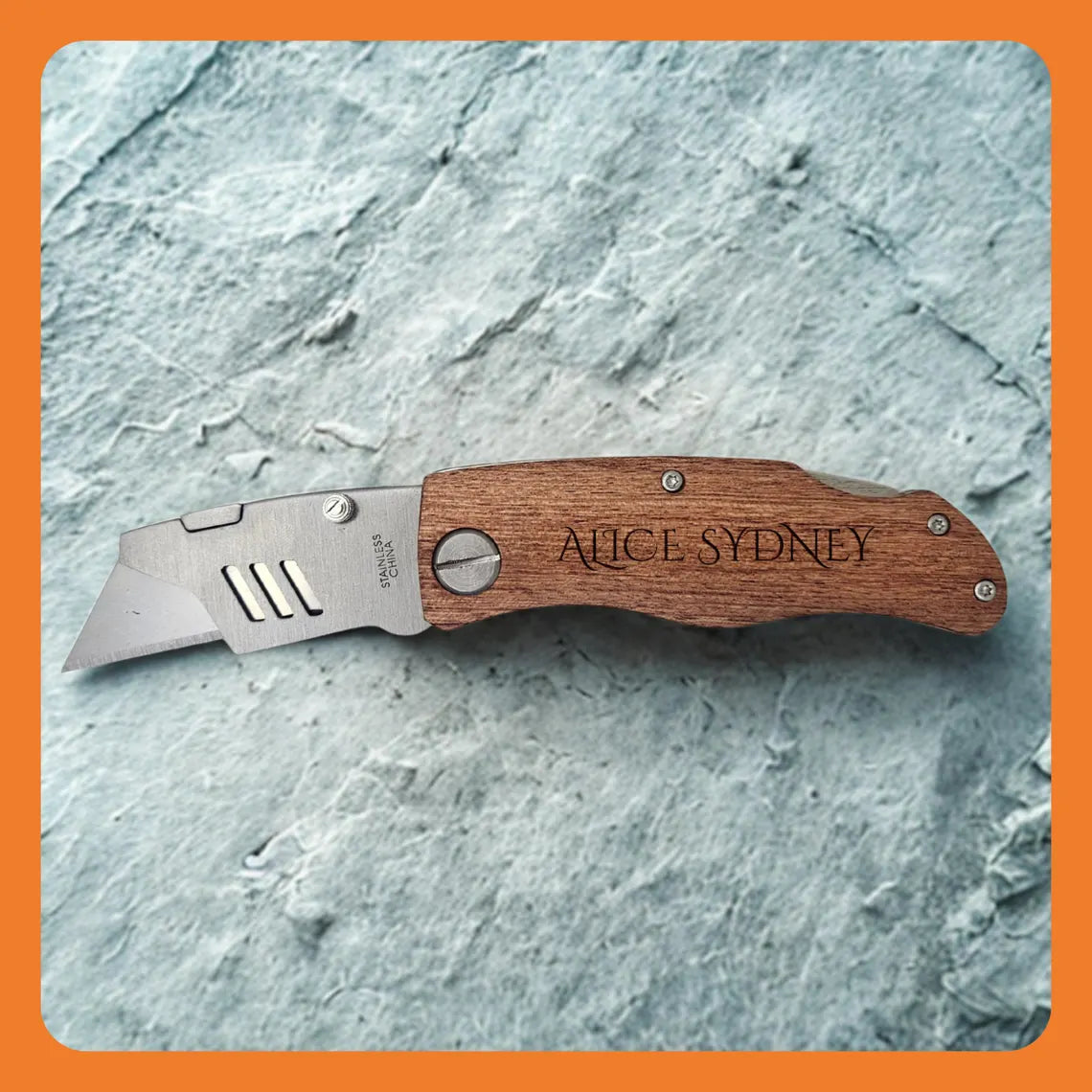 A wooden-handled folding knife with a stainless steel blade on a textured surface.