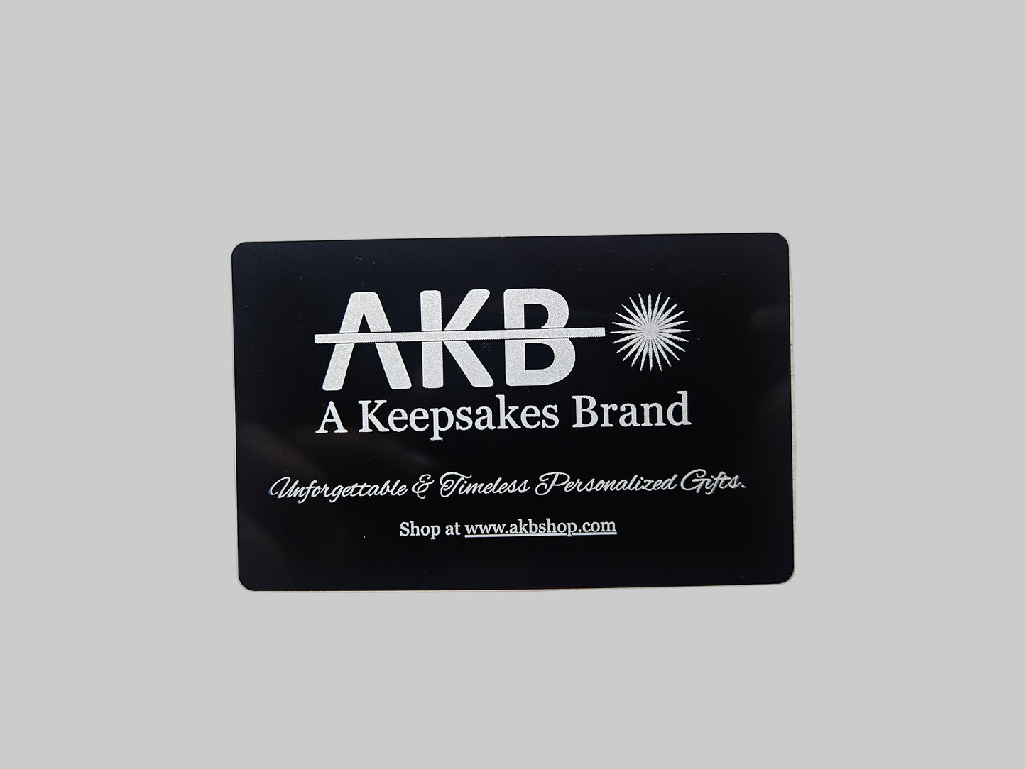 Black card with 'AKB' branding on a textured gray background