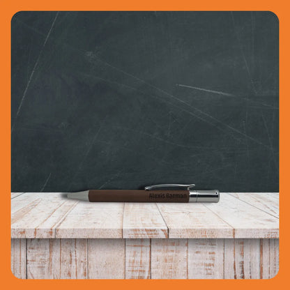 A brown pen resting on a rustic wooden table in front of a chalkboard.