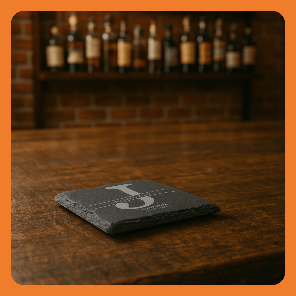 Close-up of a gray slate coaster with a design, placed on a wooden table in front of a bar shelf.