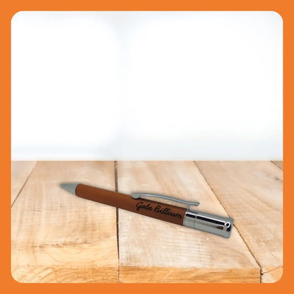 A brown pen with a silver clip resting on a wooden surface.