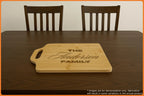 Personalized wooden cutting board on a dining table with two chairs